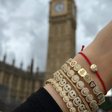 Gold bangles with British flag design on a wrist, blurred background of Big Ben.