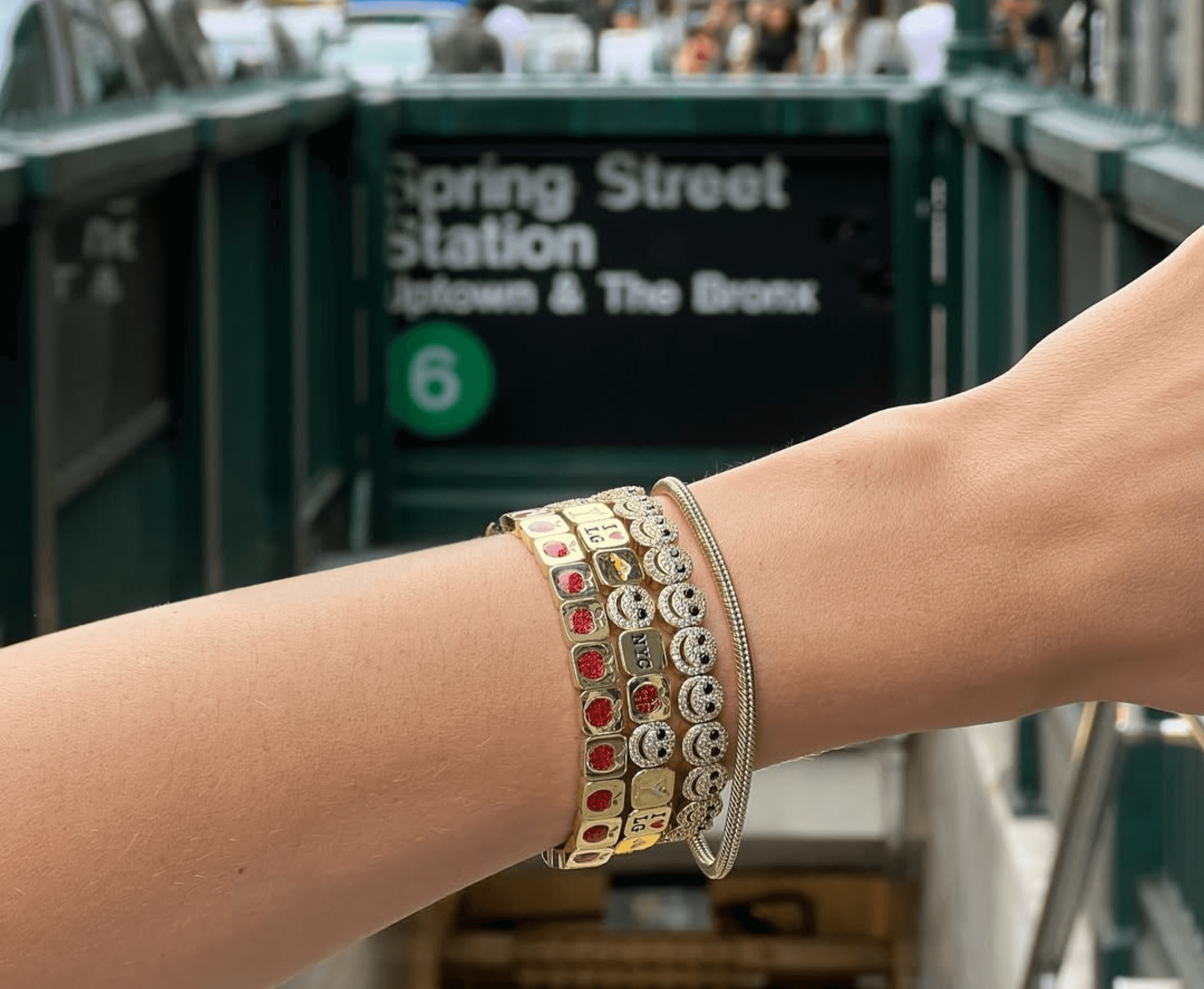 Close-up of a wrist with multiple bracelets in an urban setting