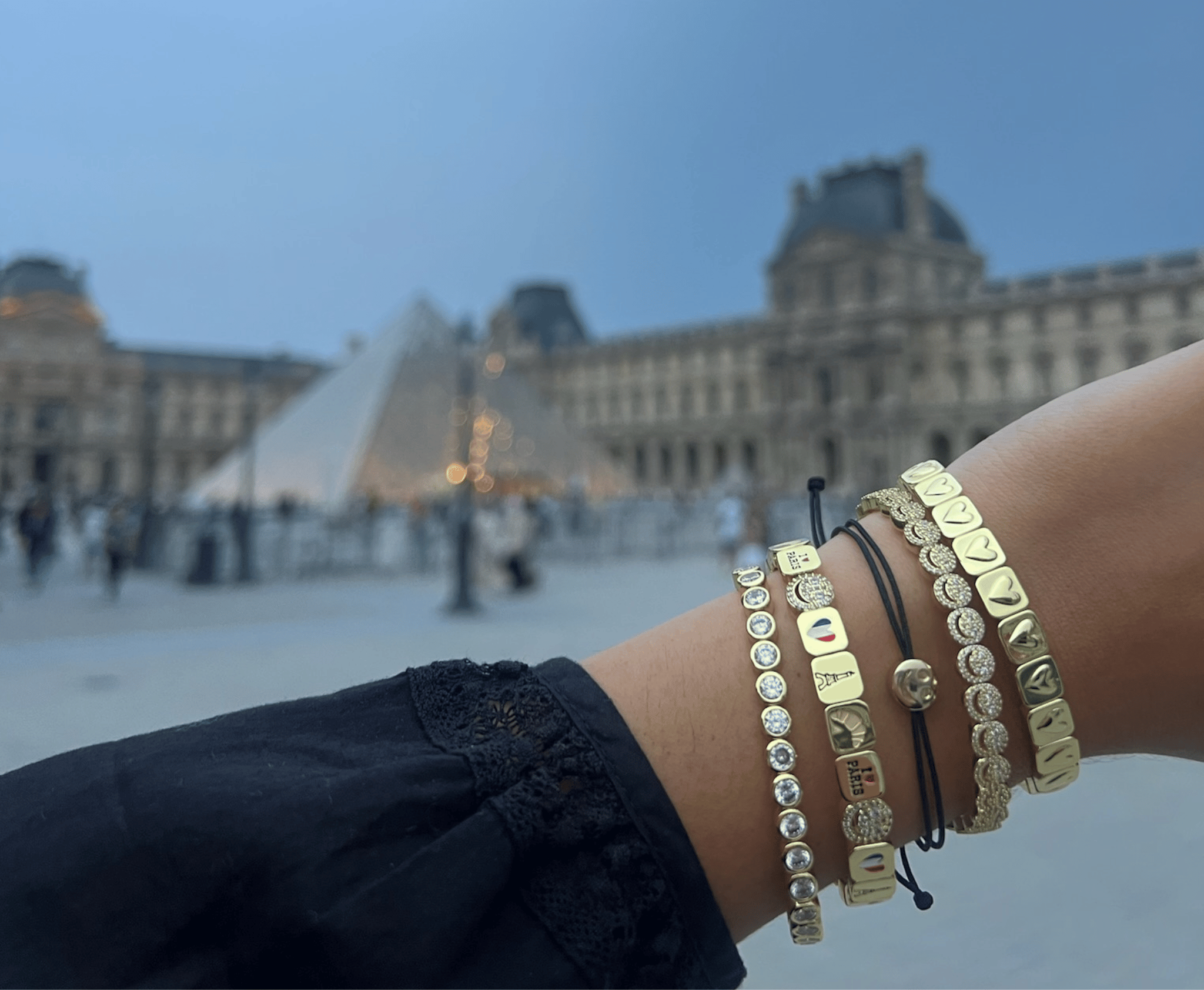 Gold bracelets on a wrist with a blurred background of a famous landmark
