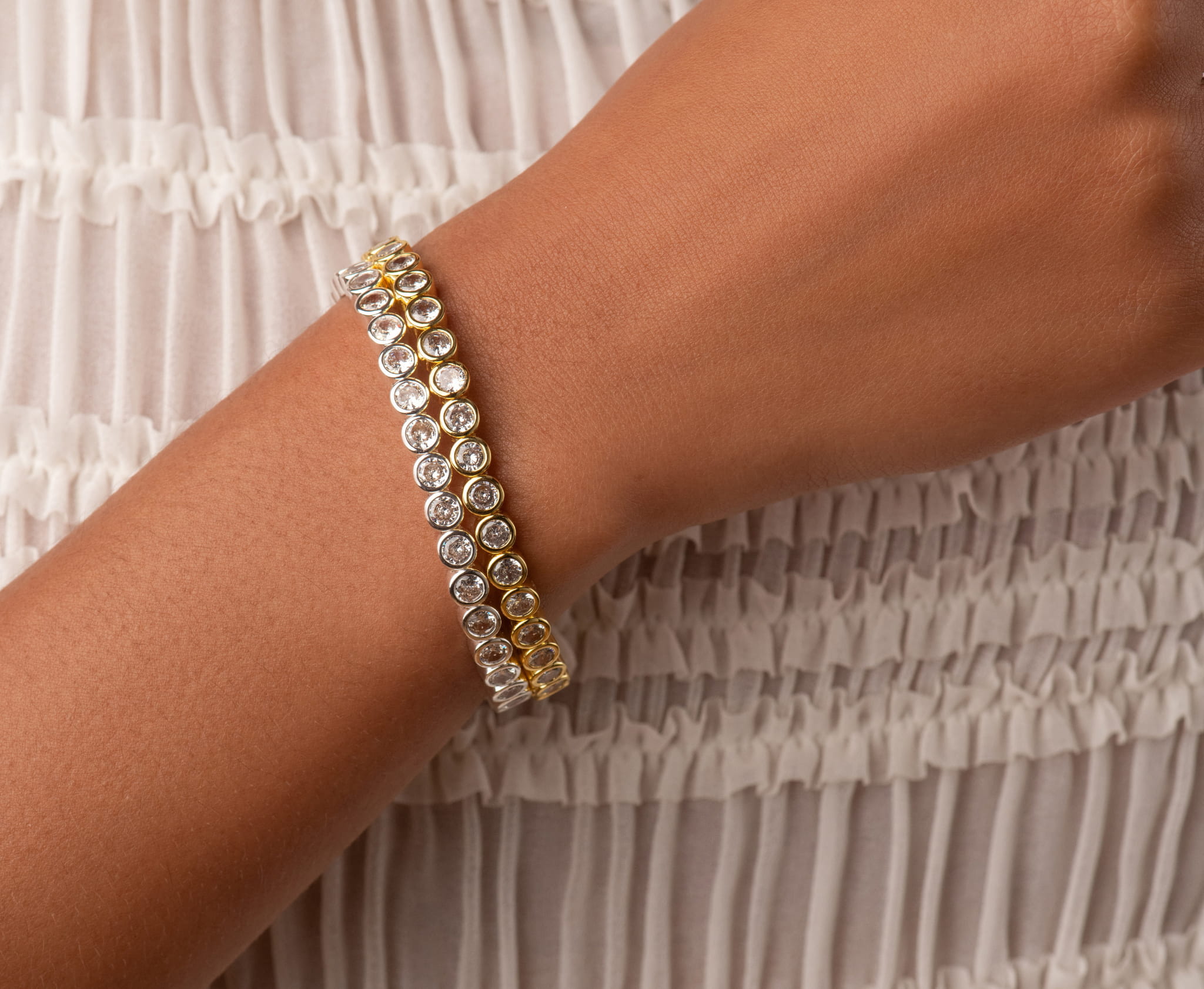 Tennis bracelet on wrist with yellow-gold setting and round clear stones