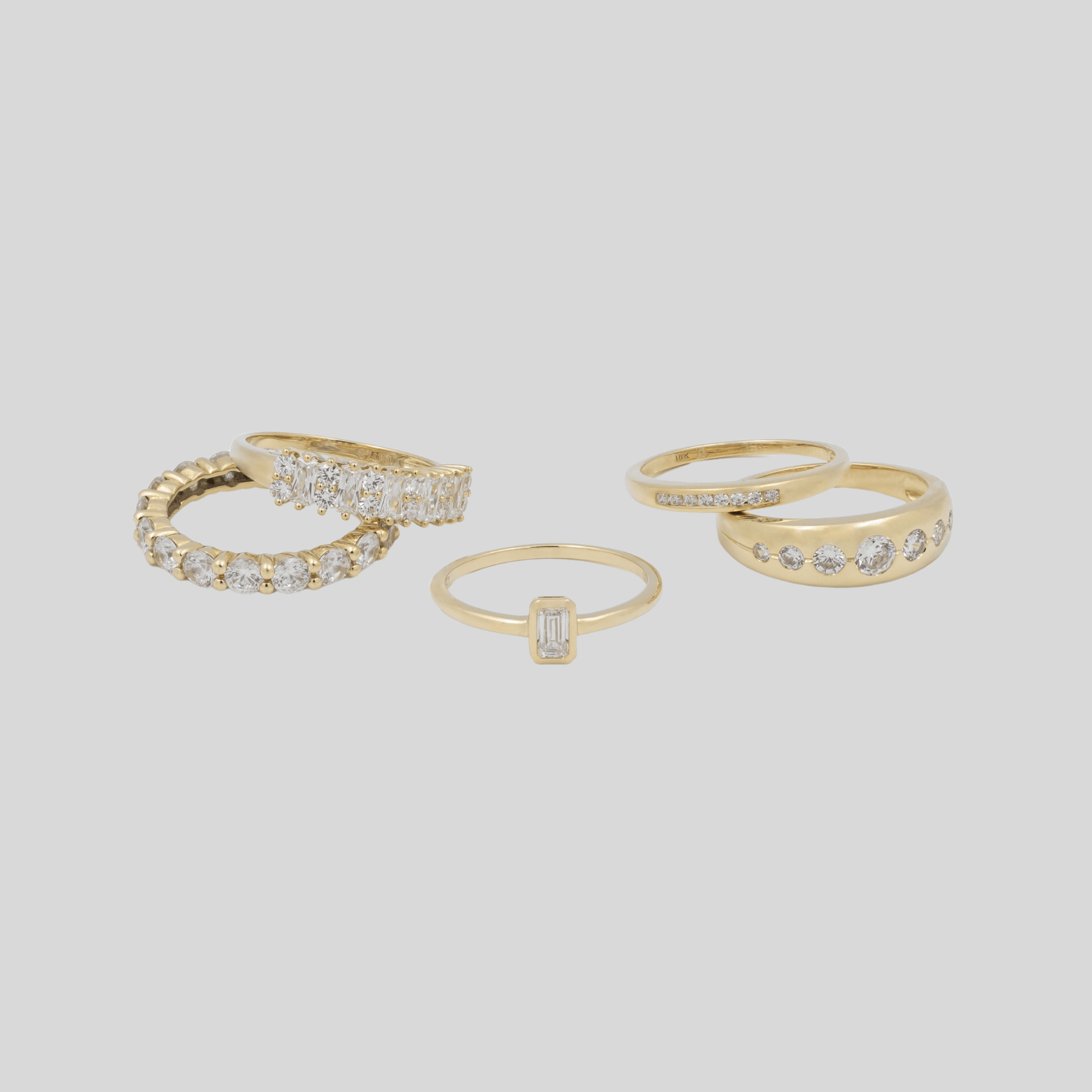 multiple gold rings on grey background with diamonds
