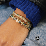 Gold-tone NHL charm bracelet with round team-logo discs on a stacked chain