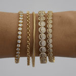 Gold bracelets with diamond accents on a wrist against a neutral background