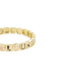 Gold beaded bracelet with engraved symbols on a white background
